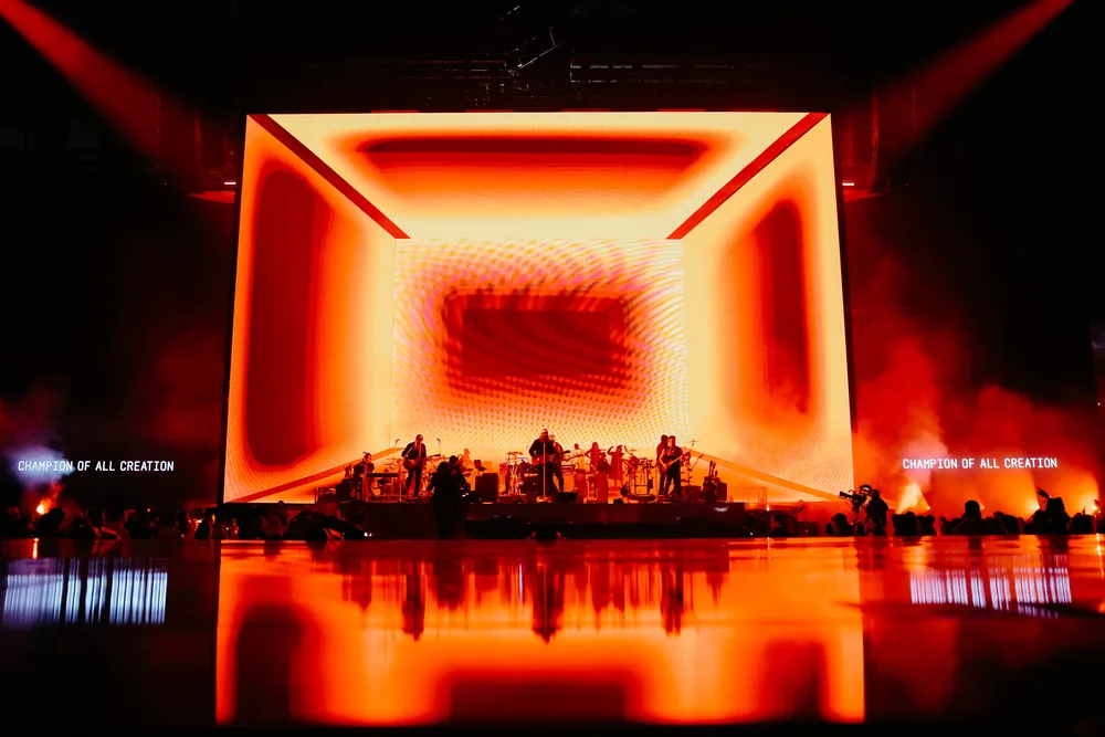 Passion 2024 stage framed by a large orange geometric video surface and haze